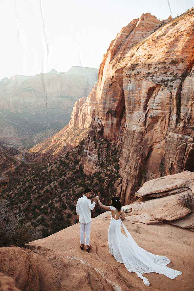 CARA MIA: Wedding photo of a couple holding hands on a mountain in the desert